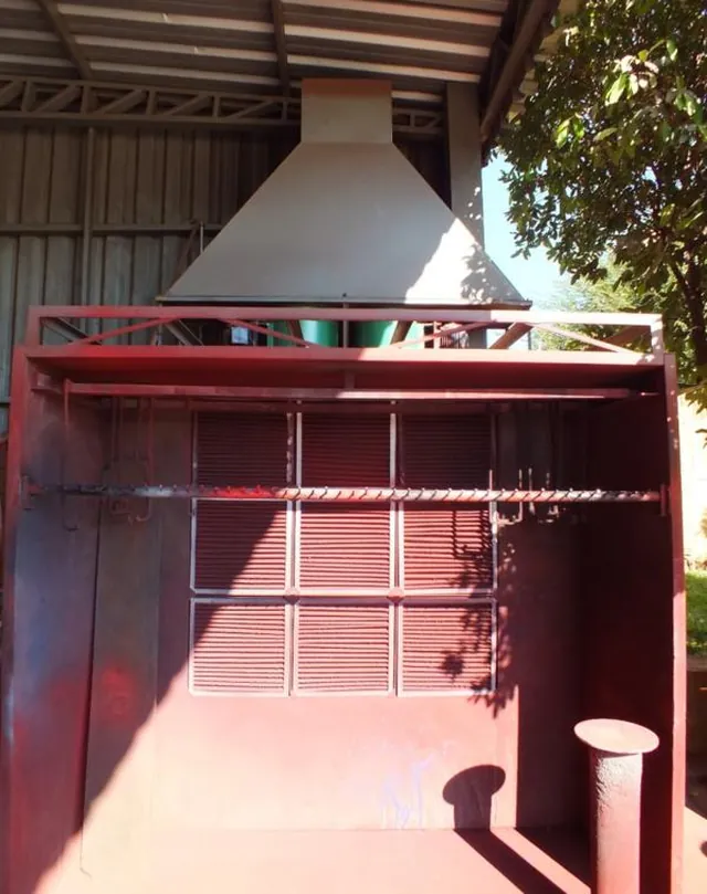 Cabine de pintura vermelha instalada no galpão, com a coifa de exaustão acima