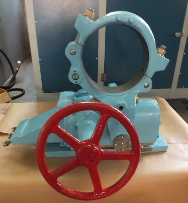 Máquina de usinagem azul-clara com volante vermelho e o anel da peça posicionado no cabeçote