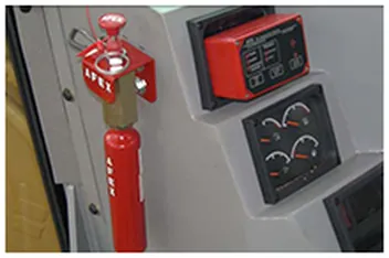 Painel de comando do sistema anti-incêndio dentro da cabine, com o acionador manual vermelho ao lado dos instrumentos