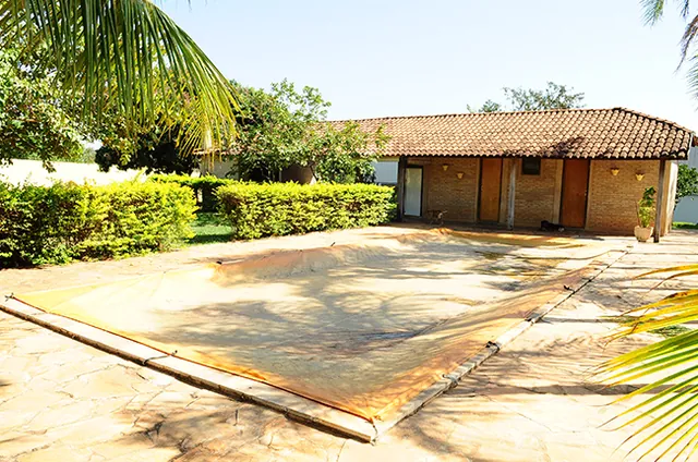 Área de lazer ao ar livre, com piso cimentado, jardim aparado e o quiosque ao fundo