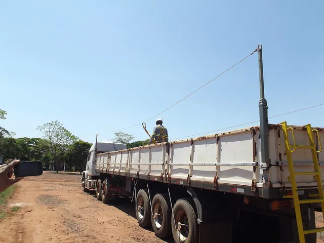 Trabalhador ancorado à haste telescópica durante serviço na carroceria do caminhão