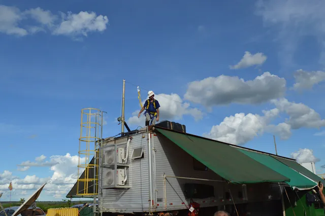 Haste telescópica de ancoragem montada sobre equipamento no campo, com o trabalhador no topo