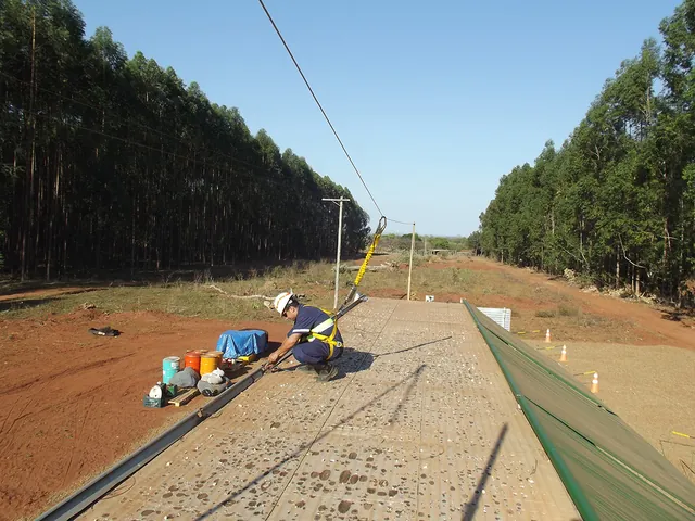 Linha de ancoragem instalada ao longo do equipamento no campo, com o trabalhador preso ao sistema
