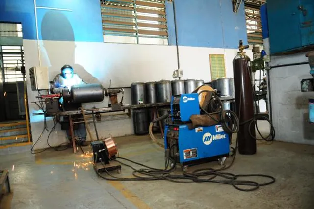 Setor de solda em operação, com o soldador trabalhando ao lado dos cilindros de gás